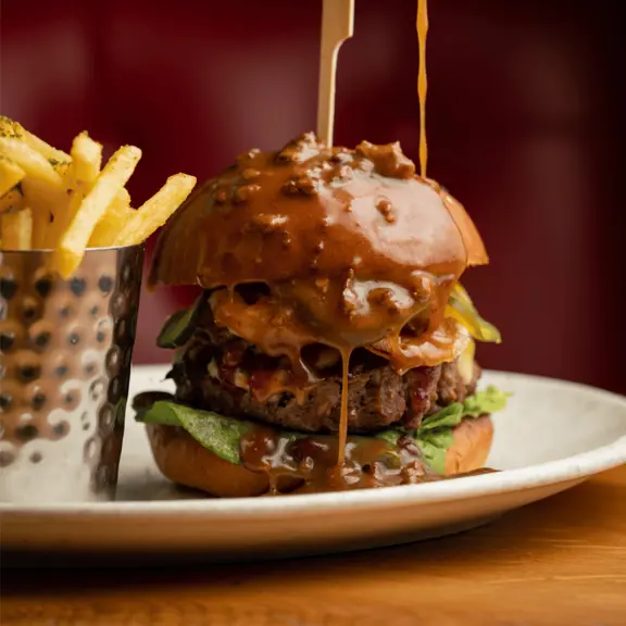 Sauce being poured on a Venison Burger